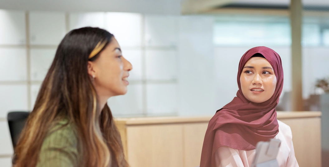 Deux femmes côte à côté à une table discutent
